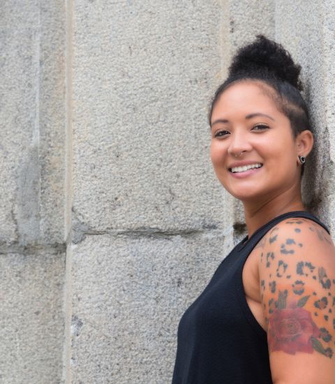 Tattooed woman leaning against wall