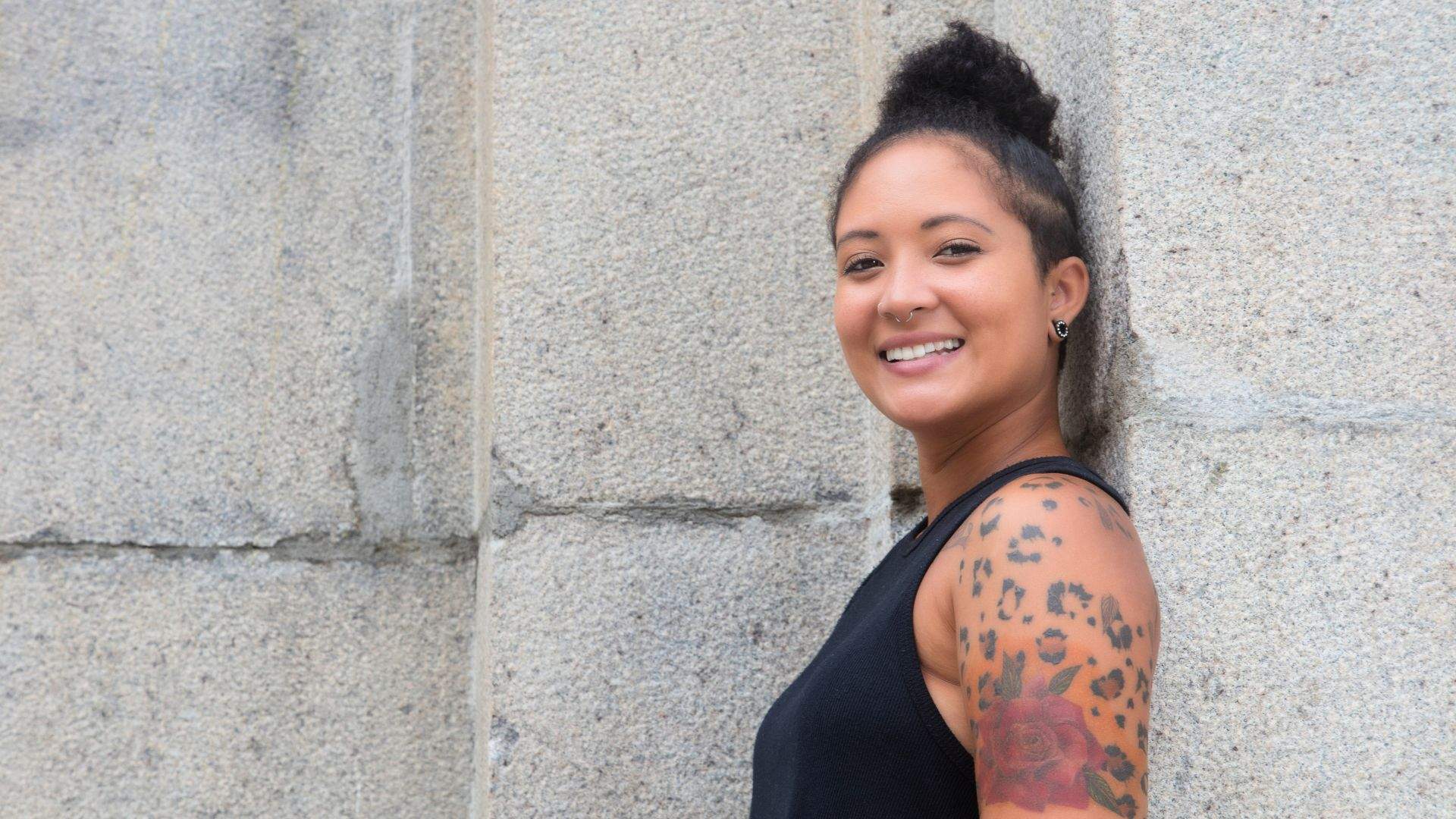 Tattooed woman leaning against wall 