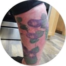 Colorful floral tattoo on a person's leg with a blurred background