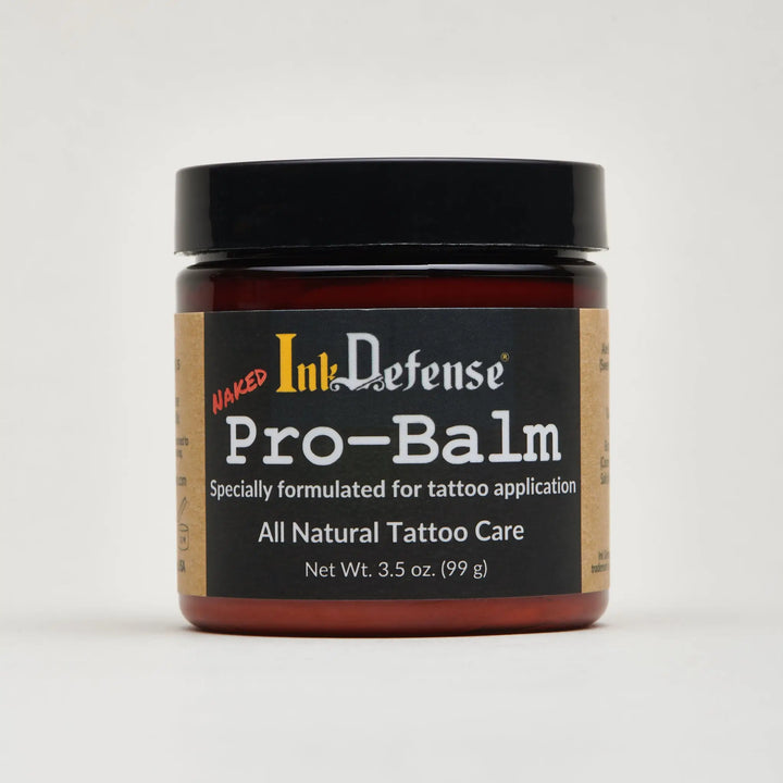 A dark amber glass jar with black lid and label of naked ink defense pro-balm all-natural tattoo care for artists