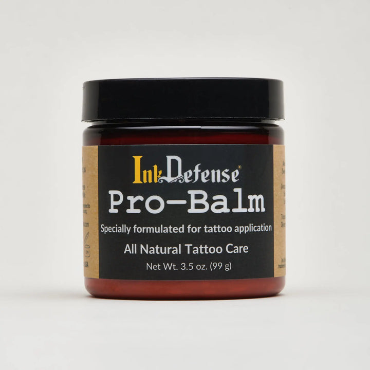 Ink defense pro-balm in a dark amber glass jar with black lid and label for all-natural tattoo care for artists
