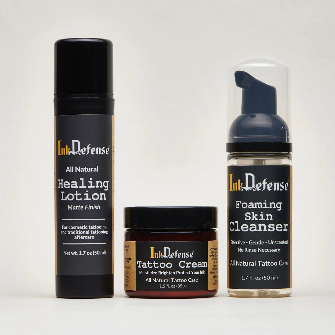 Ink defense tattoo aftercare system with matte black healing lotion, dark brown cream jar, and clear foaming cleanser bottle