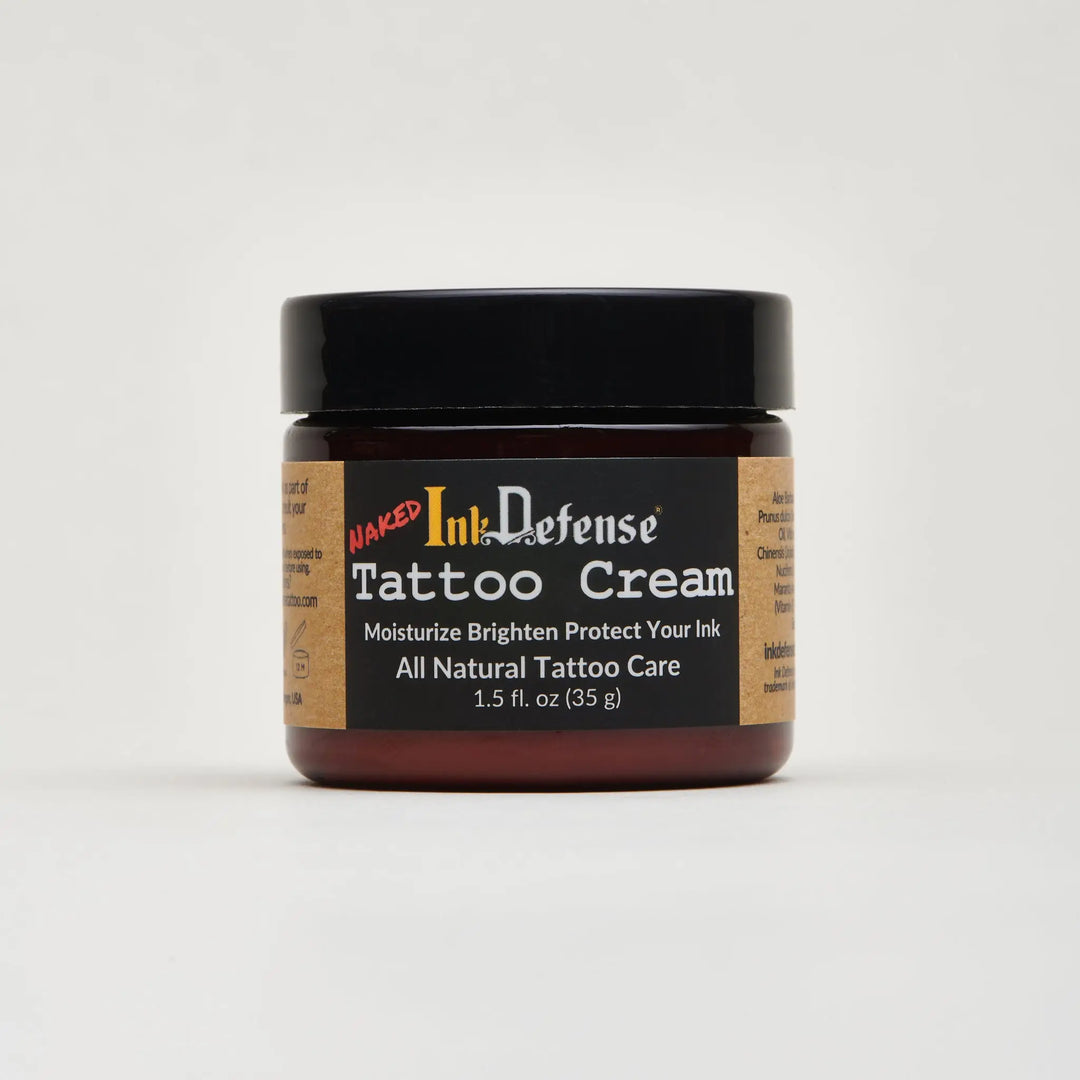 A dark amber glass jar with black lid containing naked ink defense tattoo cream for tattoo aftercare